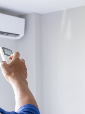 Close-up Of Man Hand Operating Air Conditioner With Remote Control.